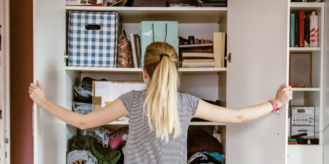 Young woman looking into her cluttered wardrobe
