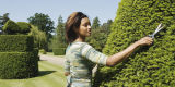 Woman trimming garden hedge